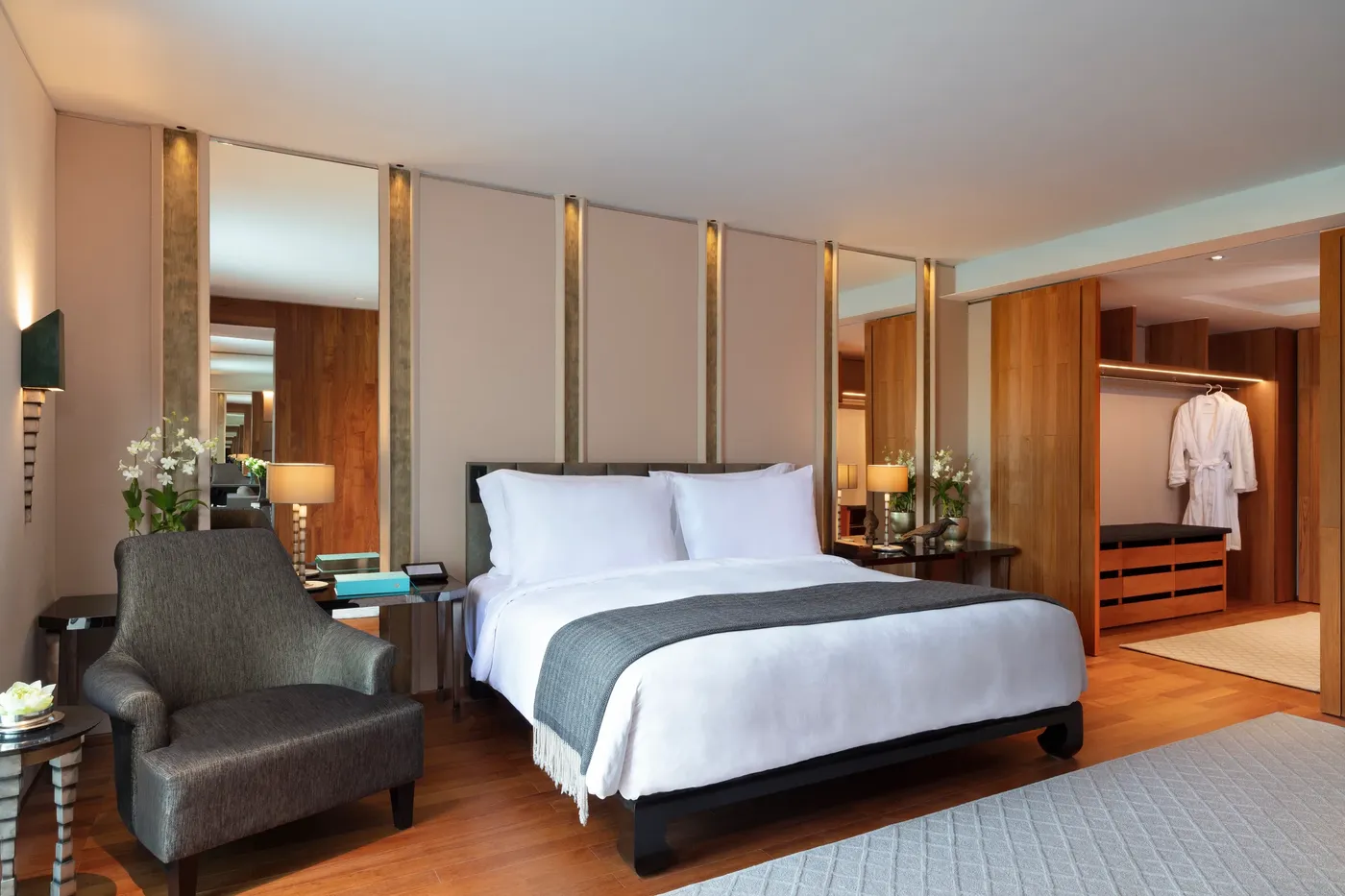 The bedroom of a Club Premier Suite at The Sukhothai Bangkok, with polished teak interiors and garden views.