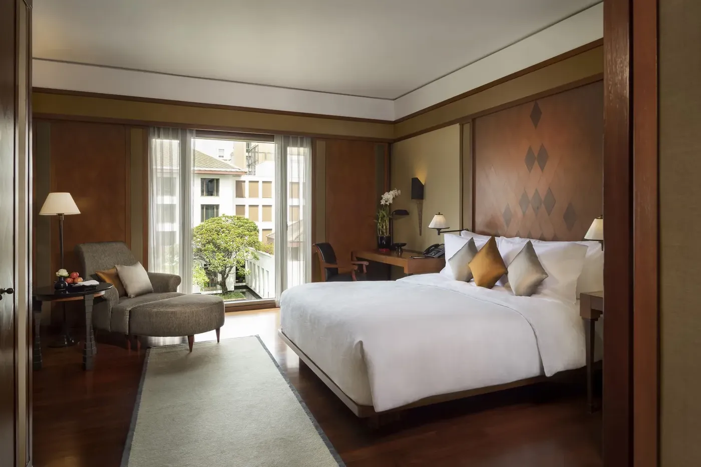 A Deluxe Room at The Sukhothai Bangkok with Thai teakwood detailing and Jim Thompson silk furnishings.