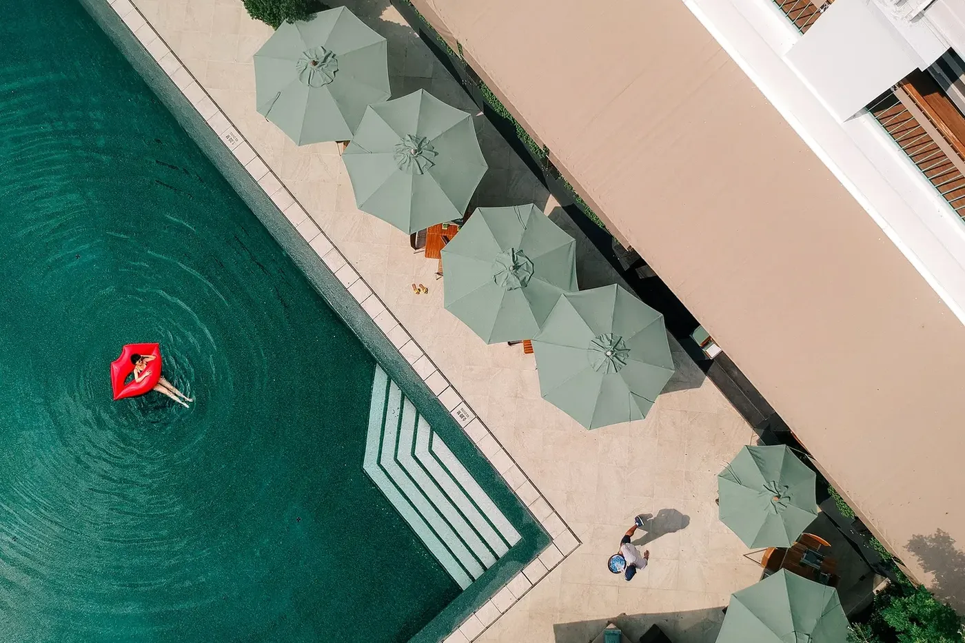 Aerial view of the landscaped garden grounds and low-rise wings of The Sukhothai Bangkok amid the Sathorn skyline.